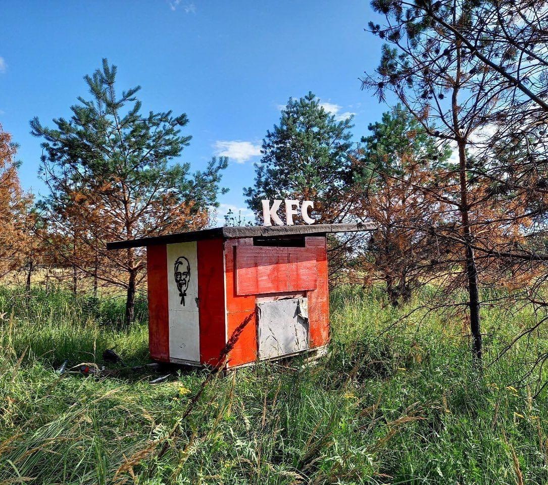 Red KFC sign on a small forest building